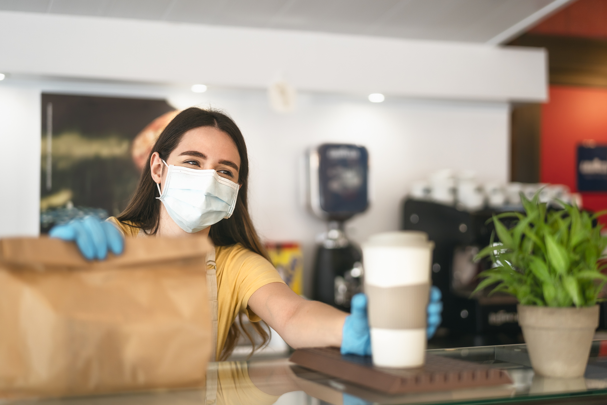 Lady barista serving up a cup of coffee and a pack of take-out food