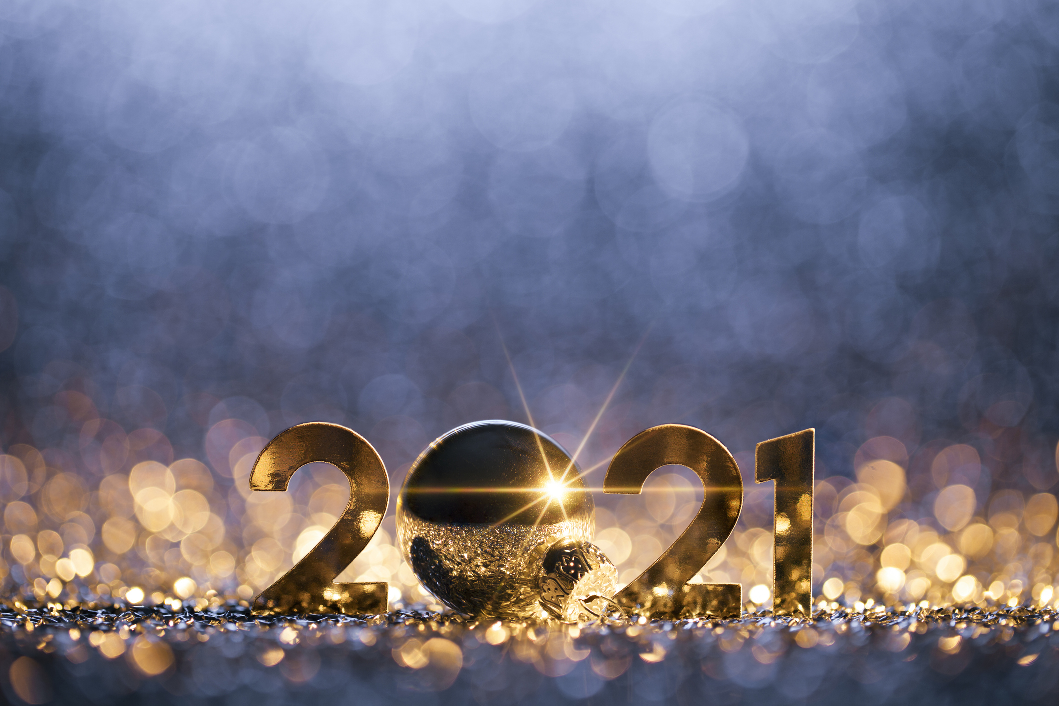 2021 displayed in golden numbers, an ornament, and glitter.