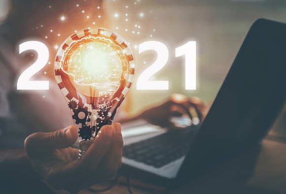 Man at laptop holds lightbulb with 2021 written across it