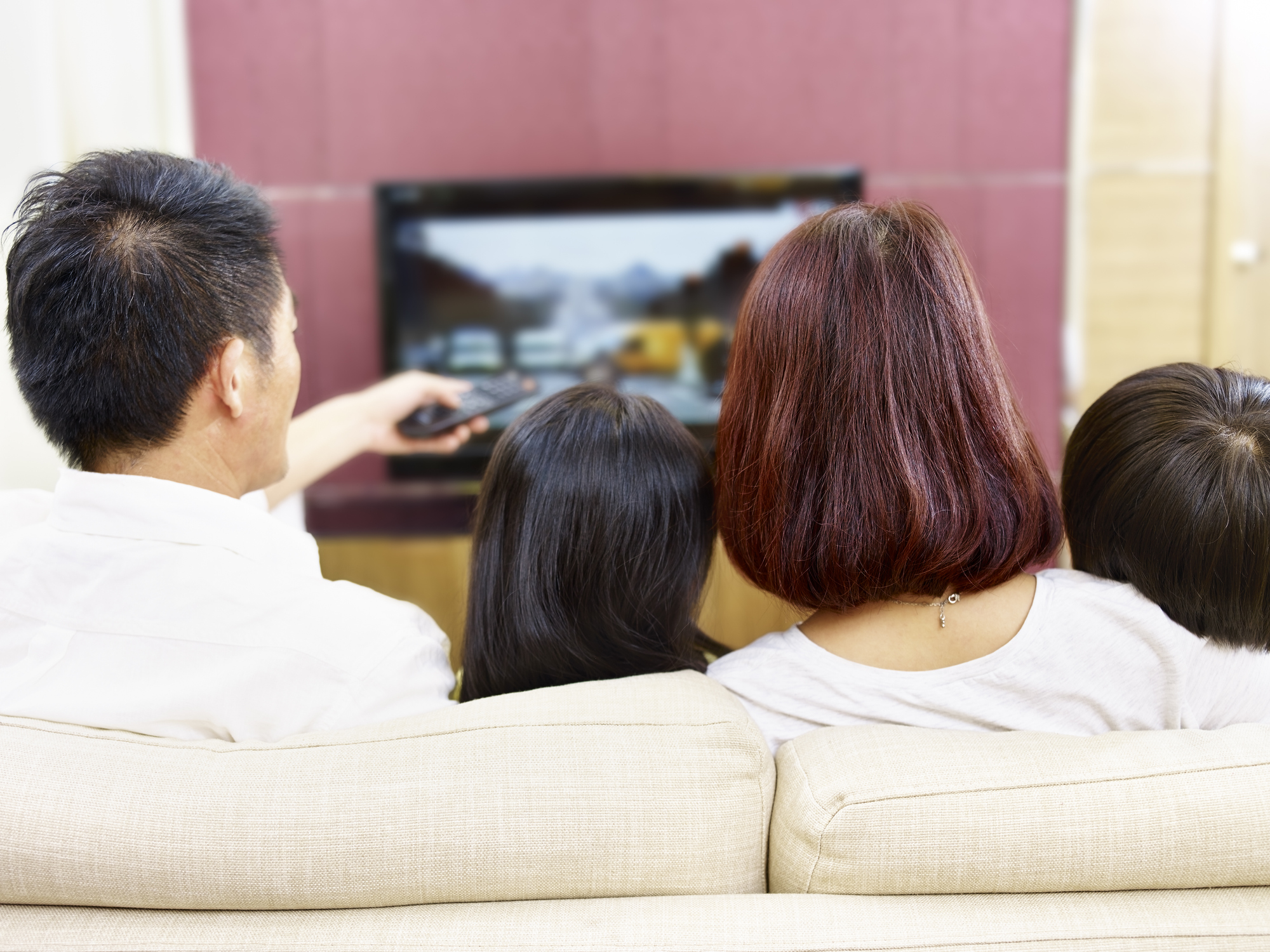 Family sitting on the couch watching television.