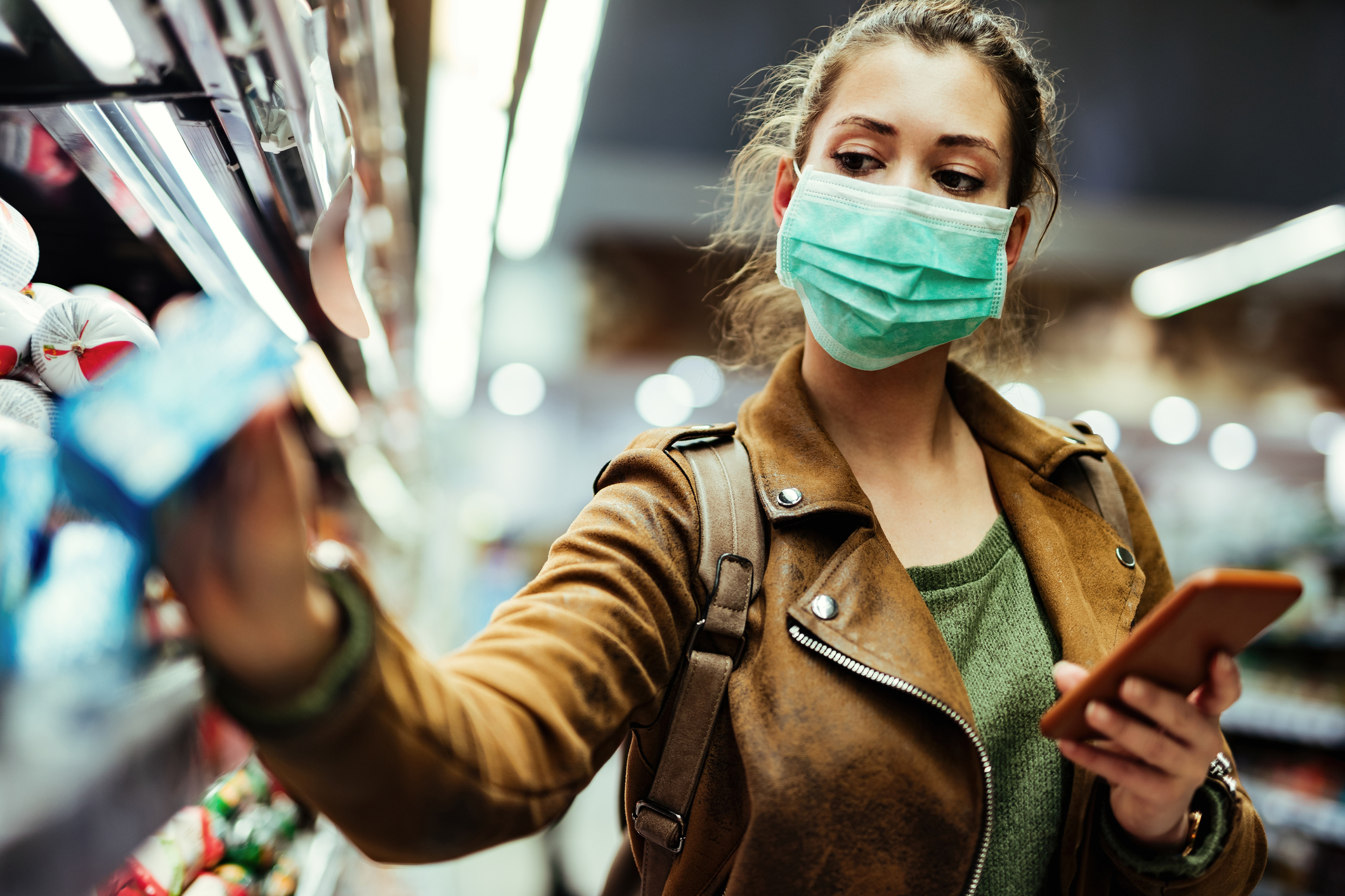 A masked woman shops for groceries.