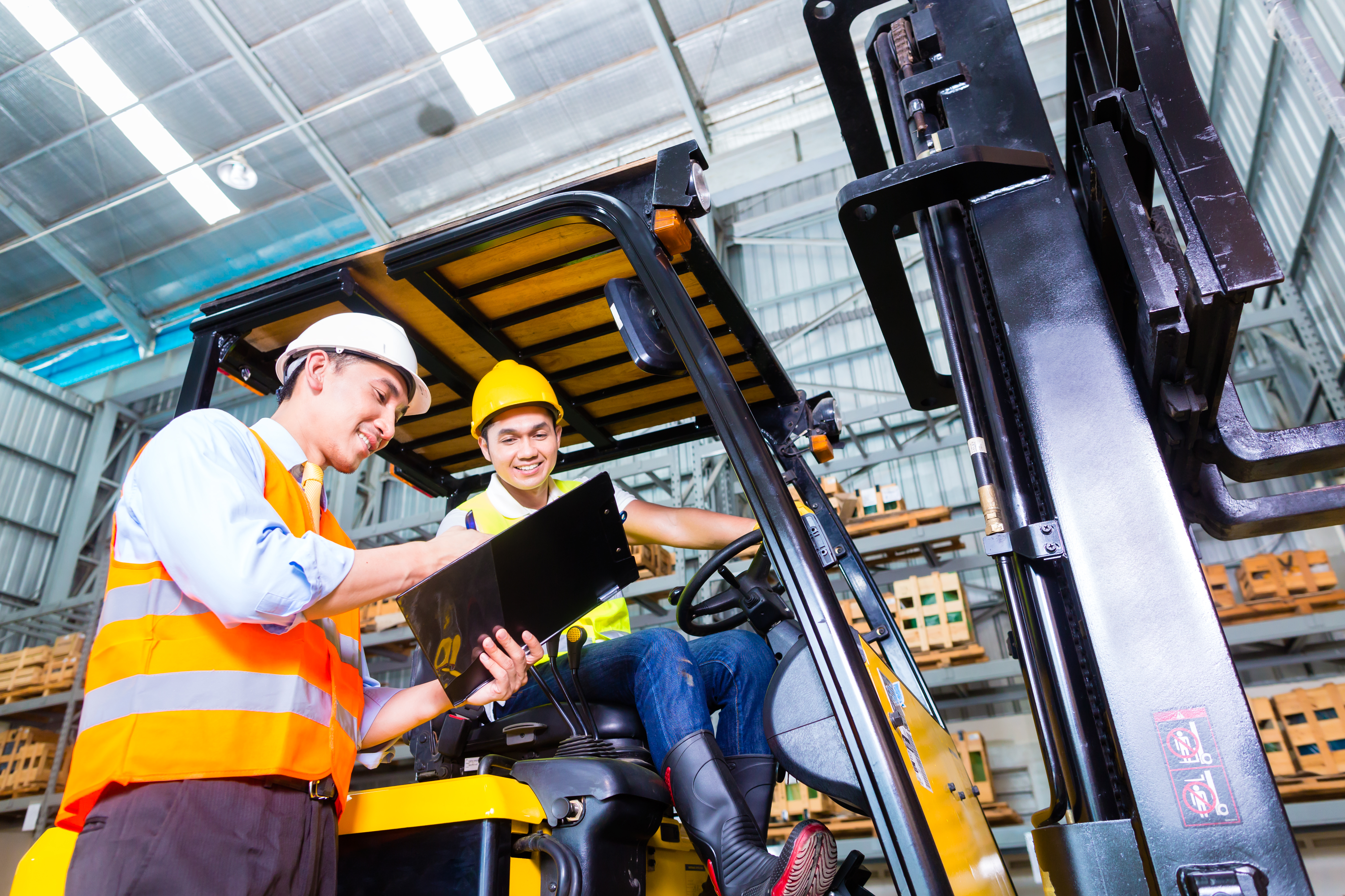 A forklift operator in a warehouse having a discussion with his supervisor.