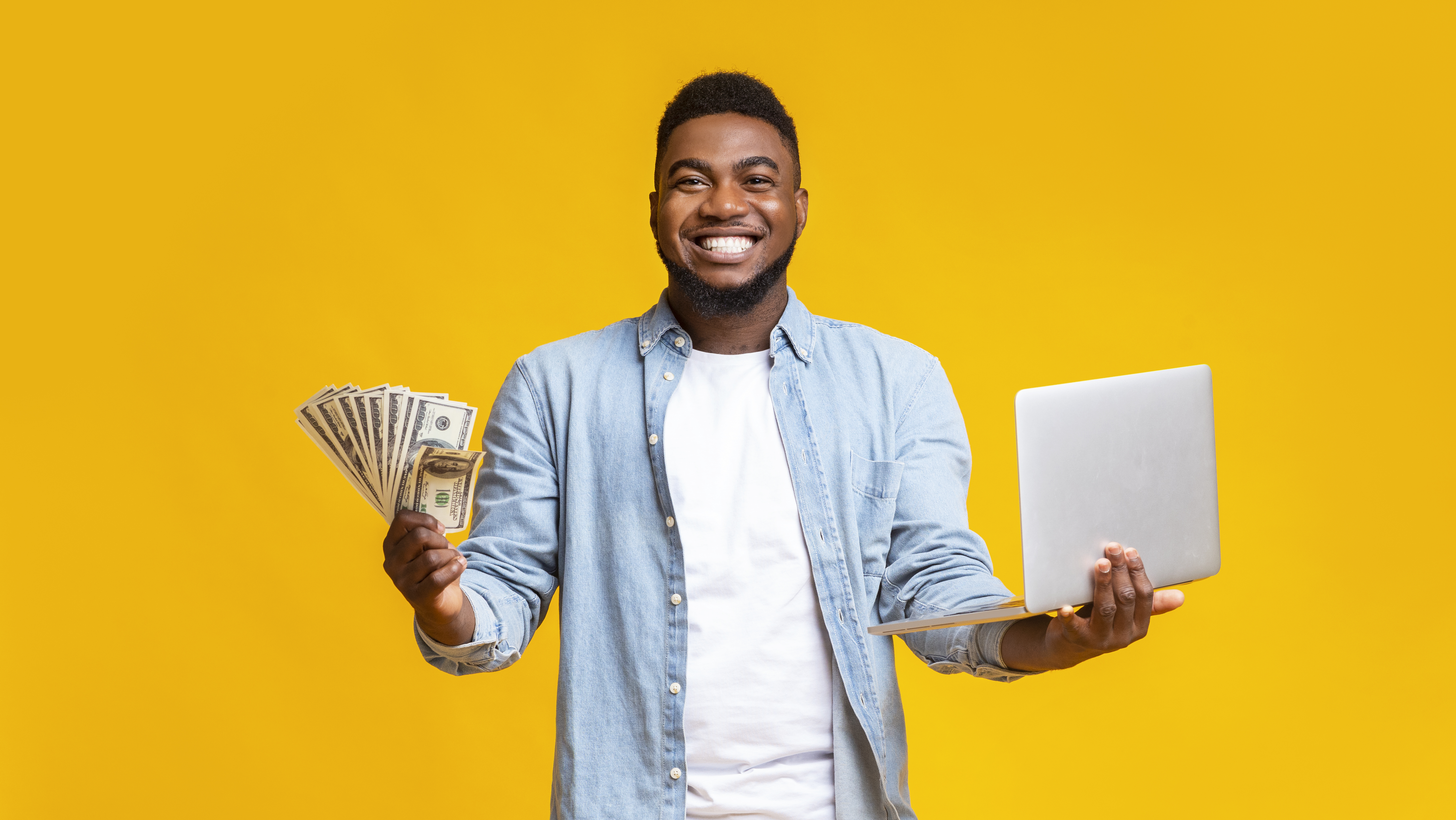 Man holding cash and laptop.