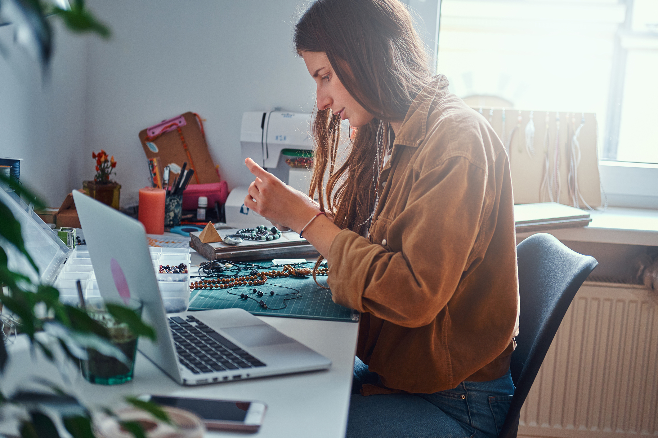 A woman creating a handmade item in front of a computer.