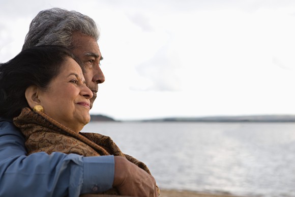 Older retired couple sitting by the water.