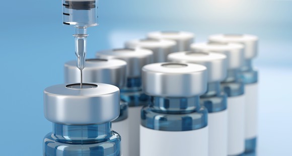 A needle is inserted in a vial that's next to other vials. 