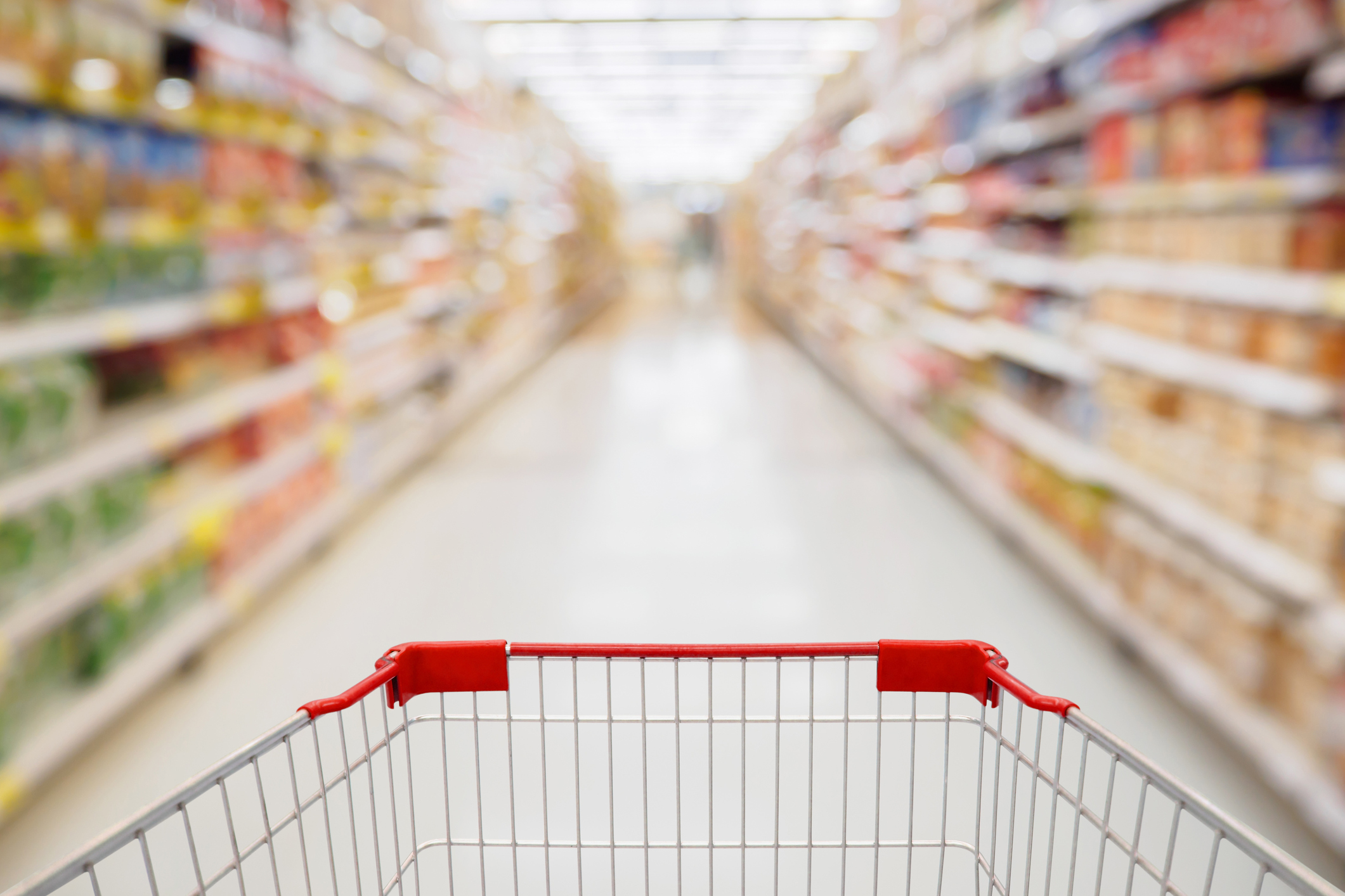 A grocery cart in a supermarket aisle.