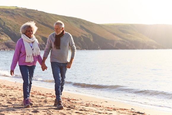 Older couple walking on the beach holding hands