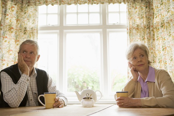 Older couple sitting at a table resting their heads in their hands