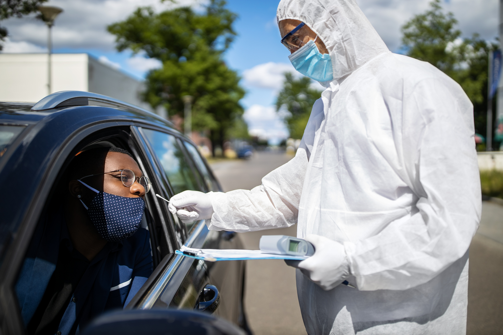Person administering COVID-19 test in a drive-thru.
