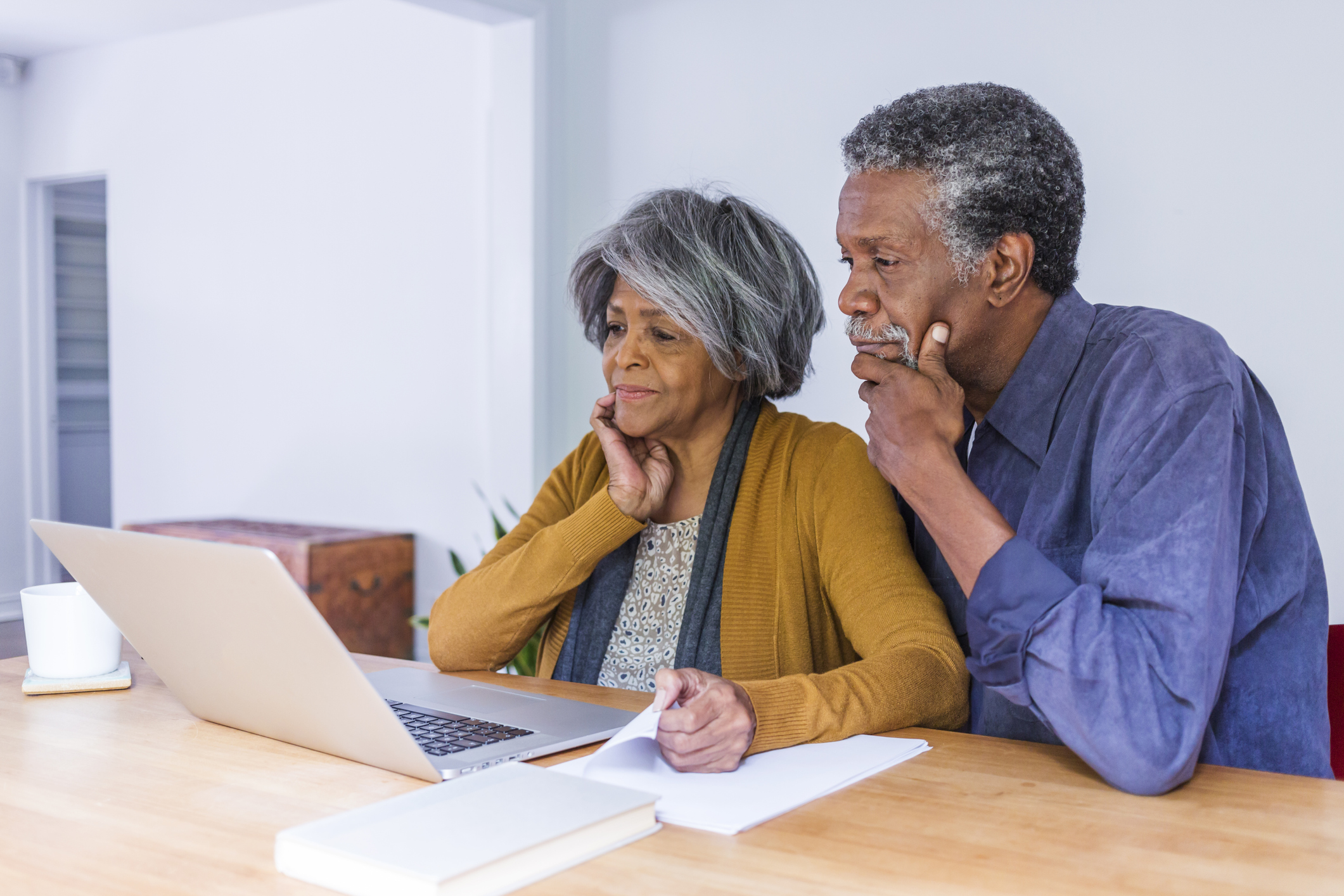 Older couple looking at laptop with concerned expressions.