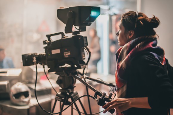 A woman behind a film camera.