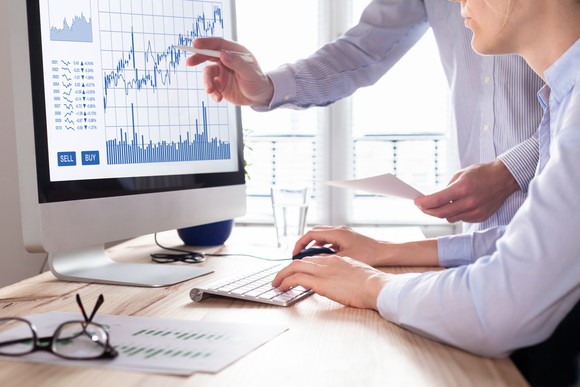 Businessman pointing to financial chart on monitor. 