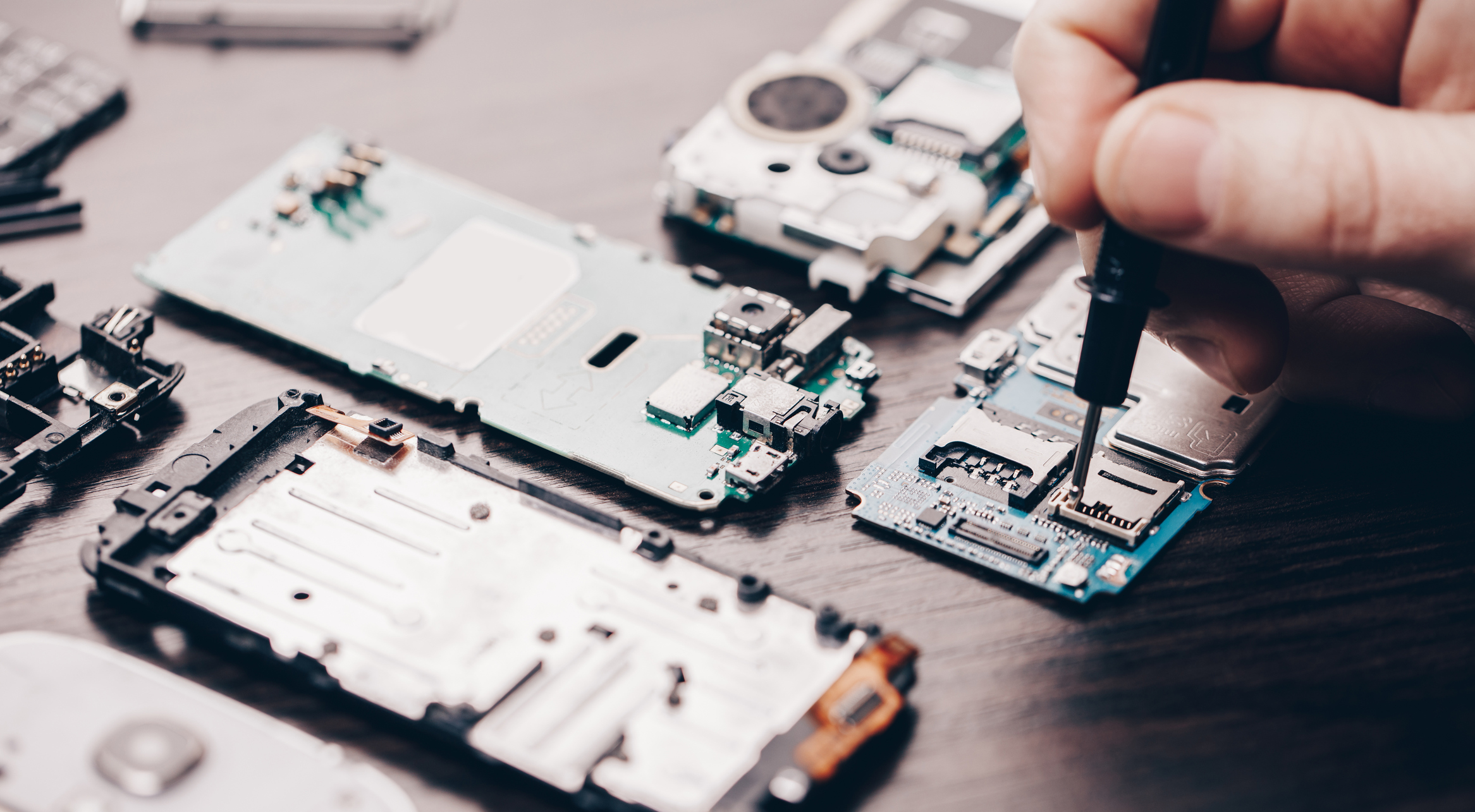 A man repairs a disassembled smartphone.