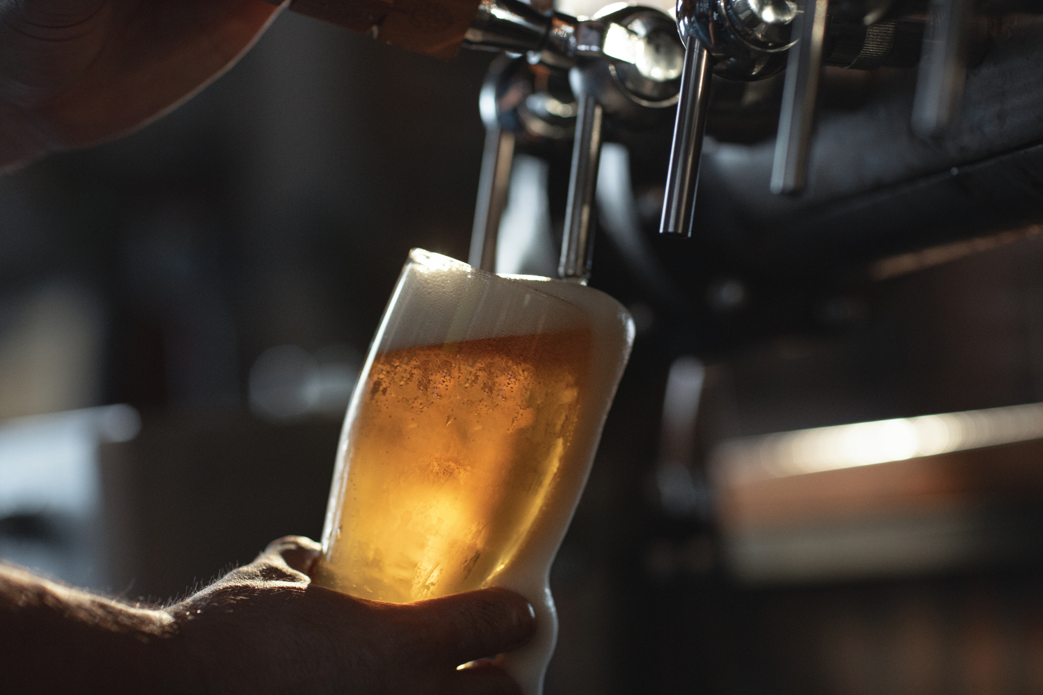 Someone filling glass of beer from tap