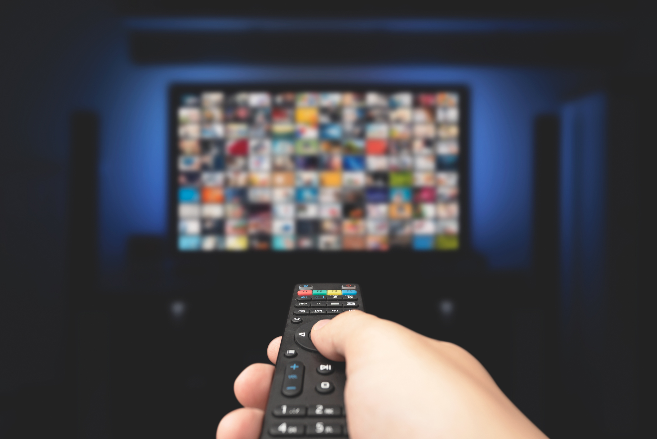 A hand holding a remote pointing at a TV