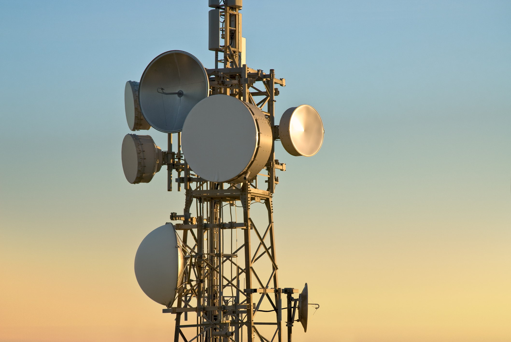 A cellular tower with multiple attached satellite dishes.