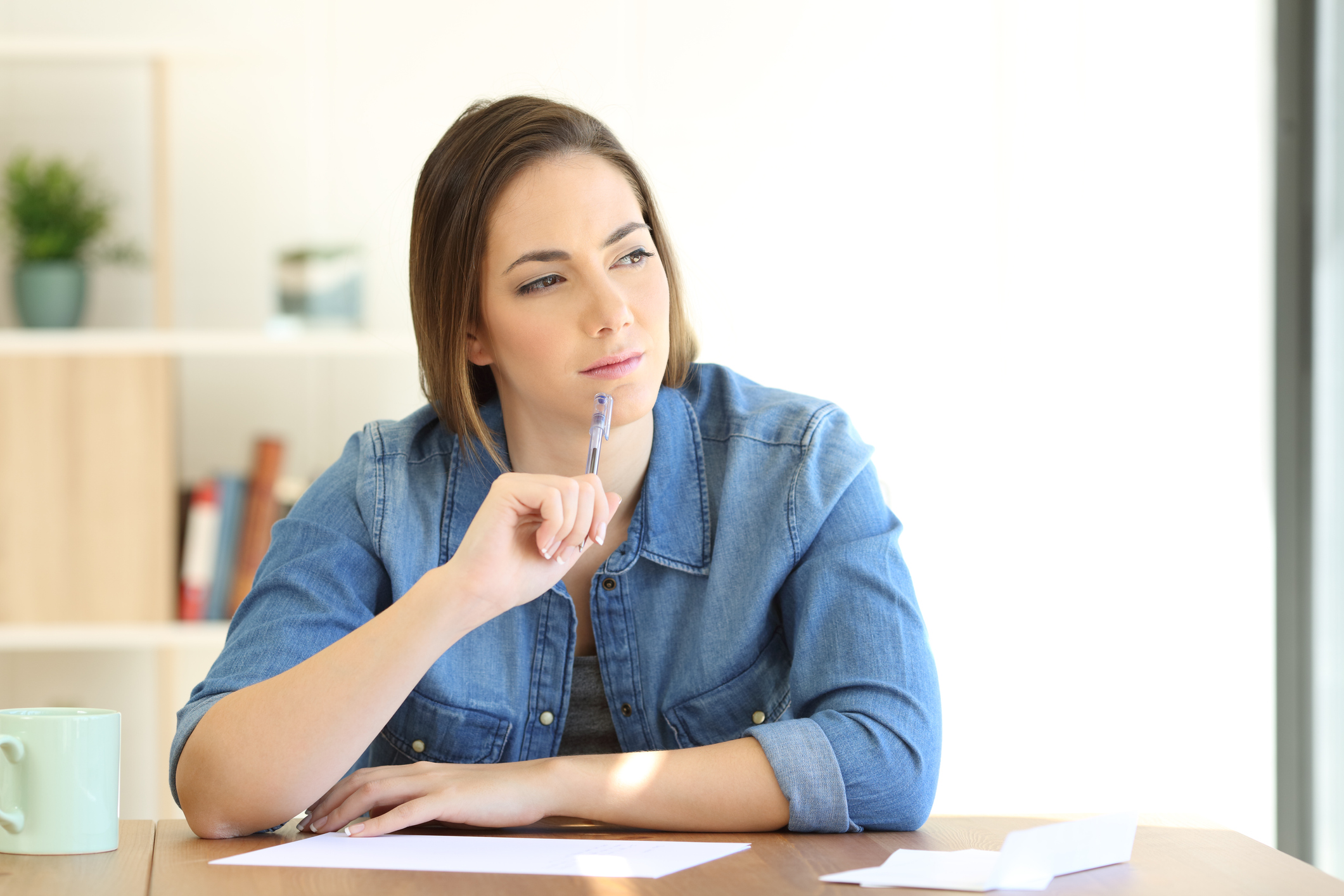 A young woman squints in deep thought, tapping a pencil on her chin.
