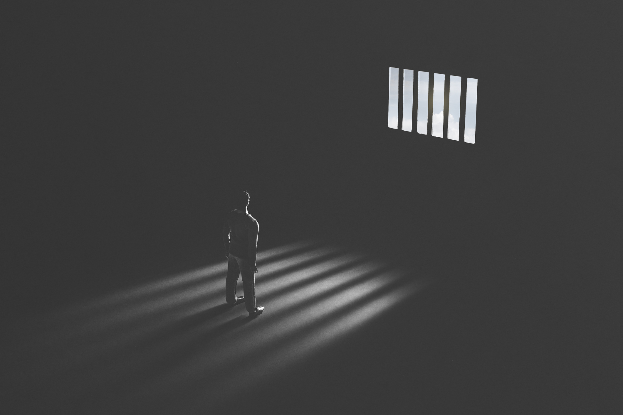 Black and white picture of a prisoner staring through a jail cell window