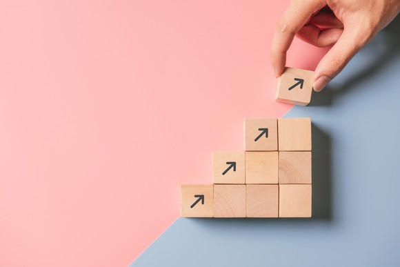 Hand stacking wood blocks with arrows pointing upward