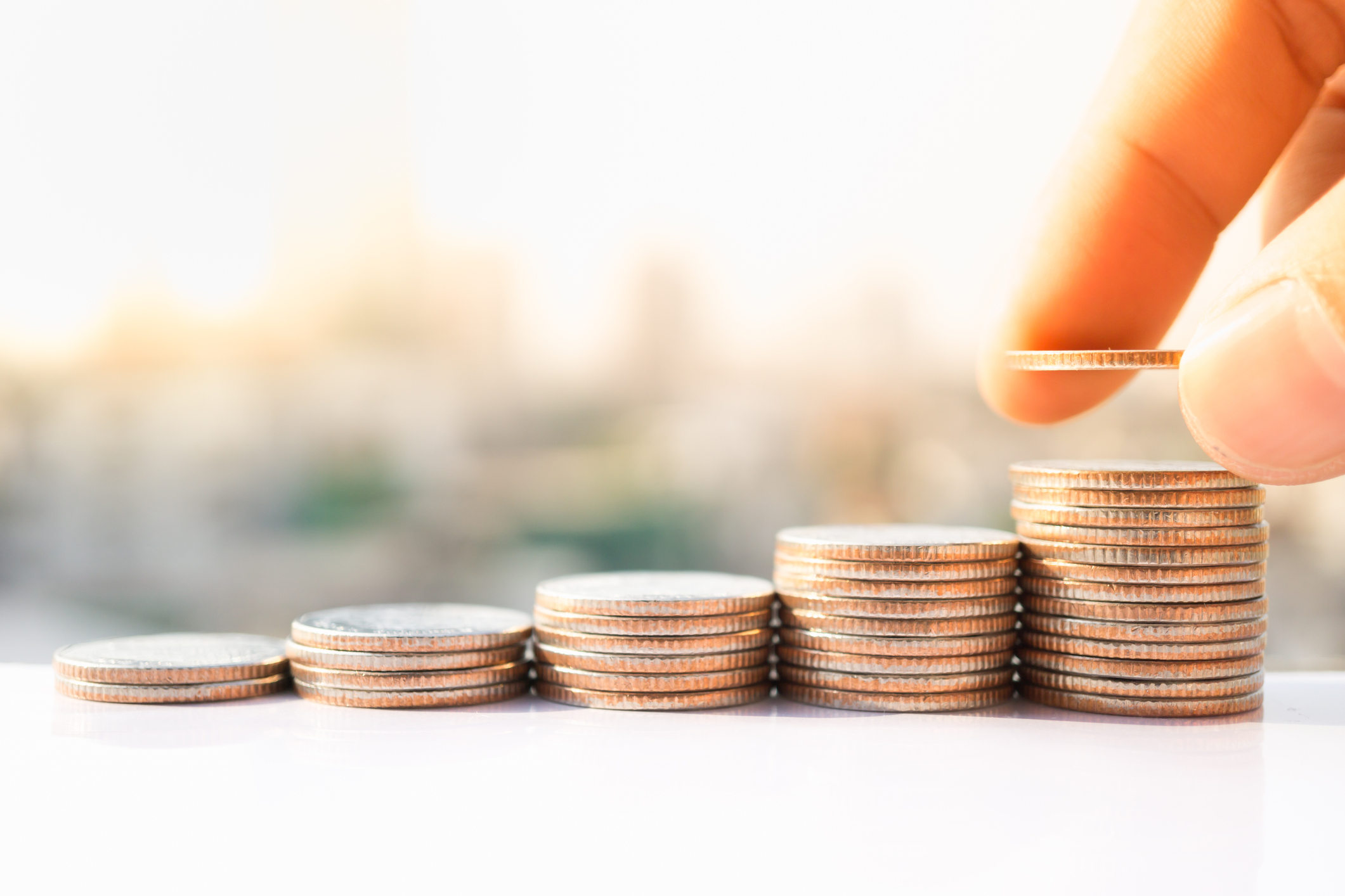 Man's hand put money coins to stack of coins.