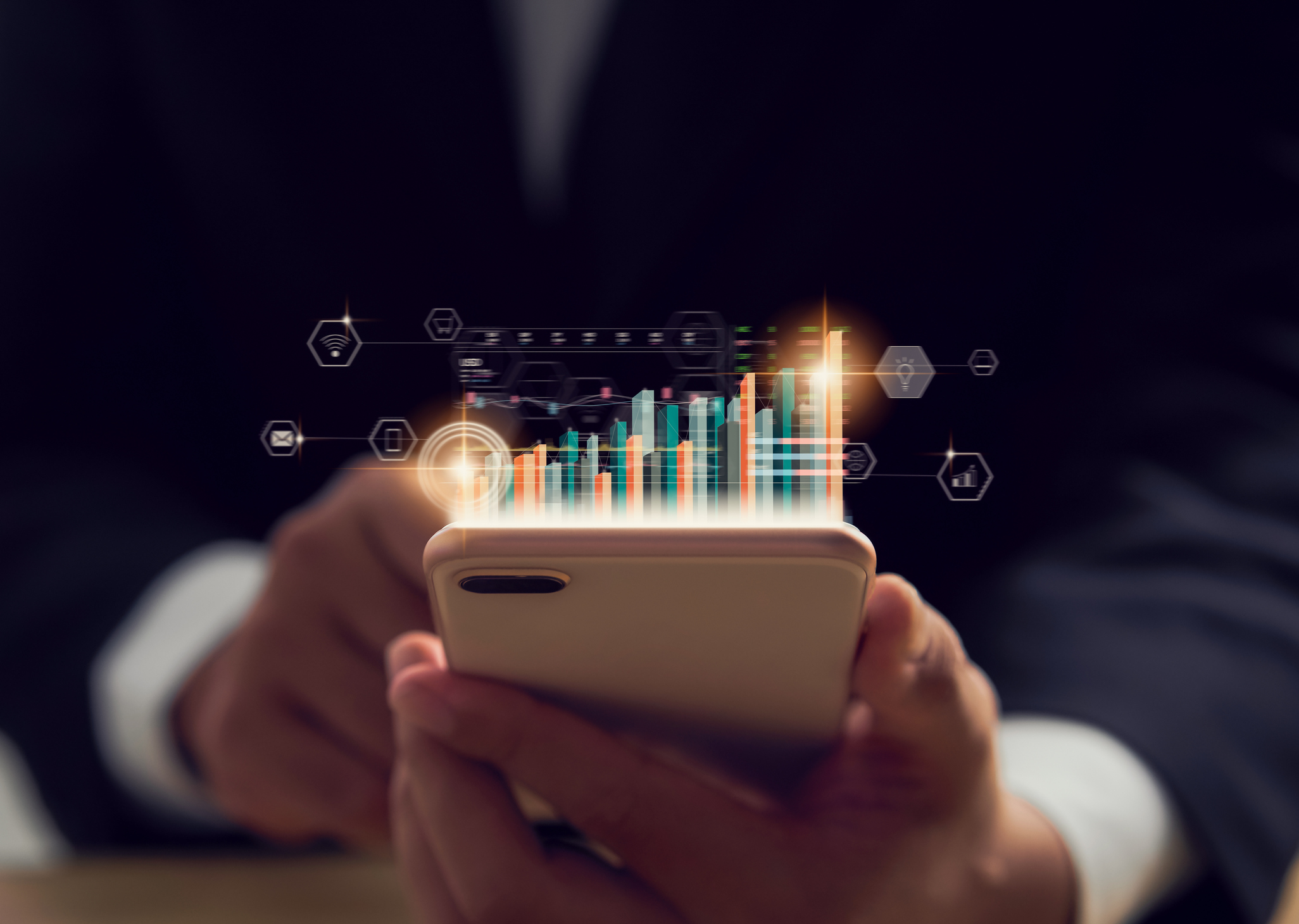 Person using smartphone with graphs projected off the screen.