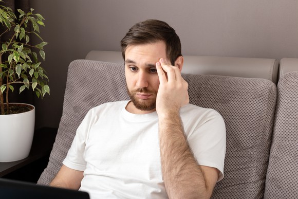 An investor looking worriedly at a laptop. 