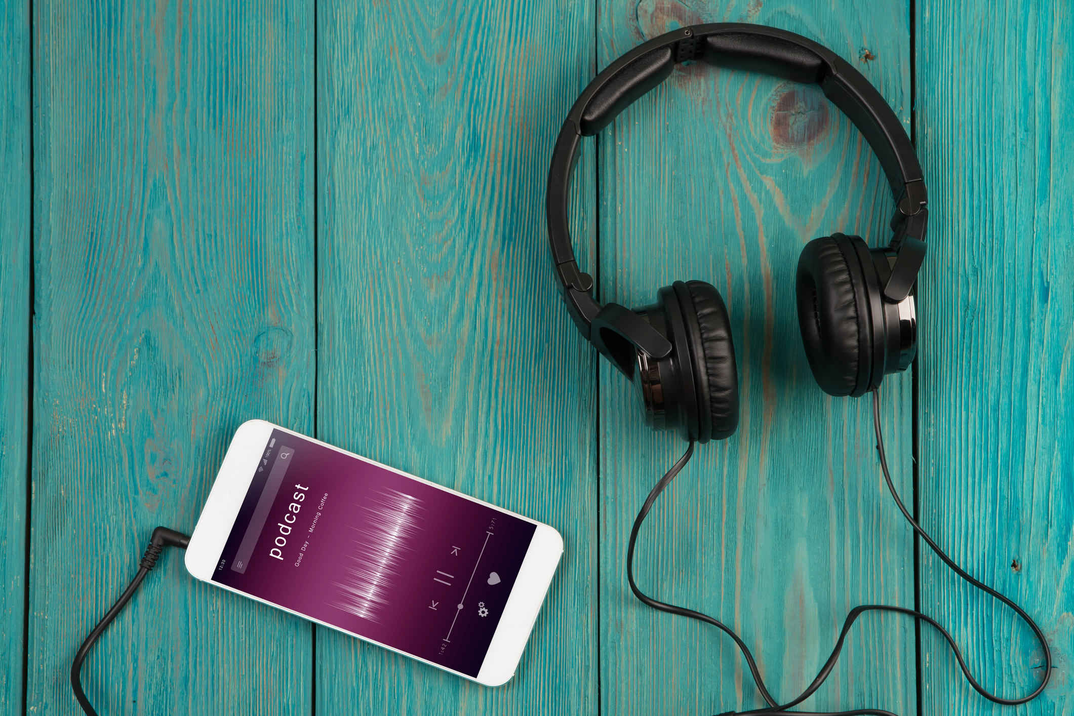 Smartphone and headphones on a wooden table.