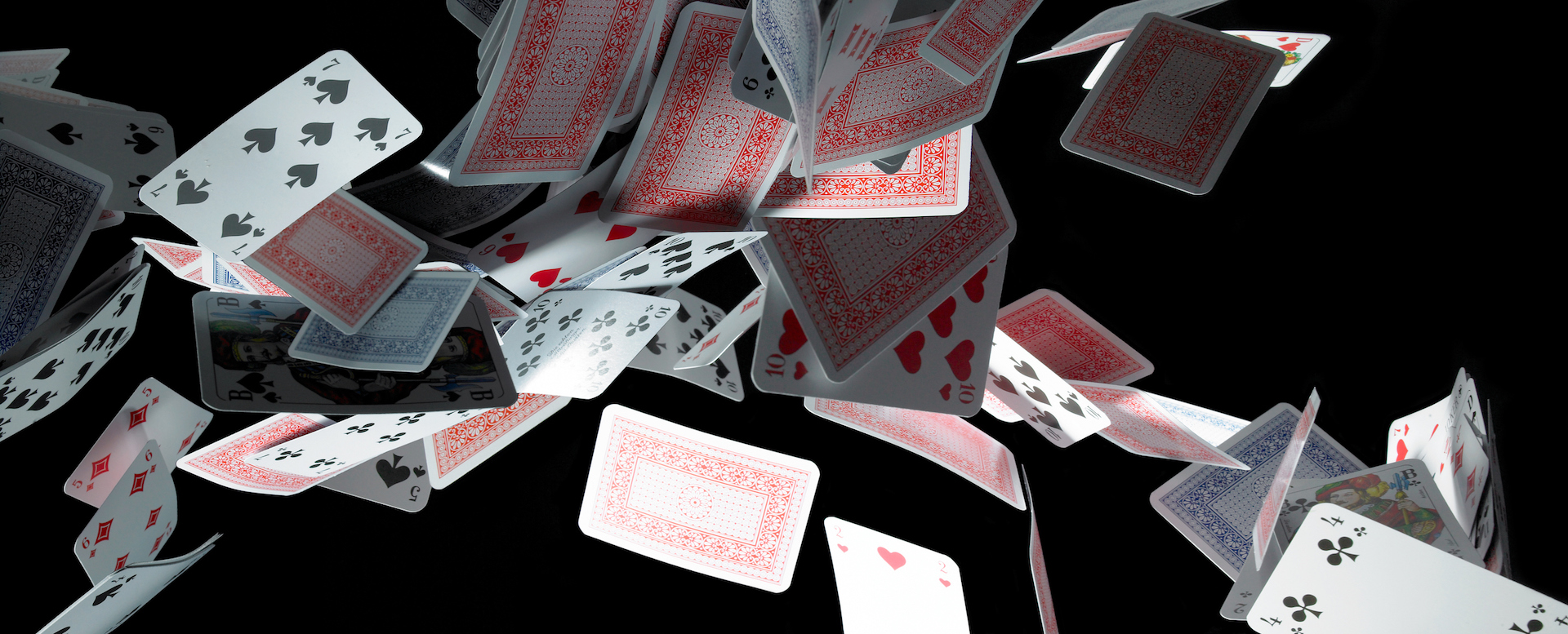 A deck of cards falling on a black surface.