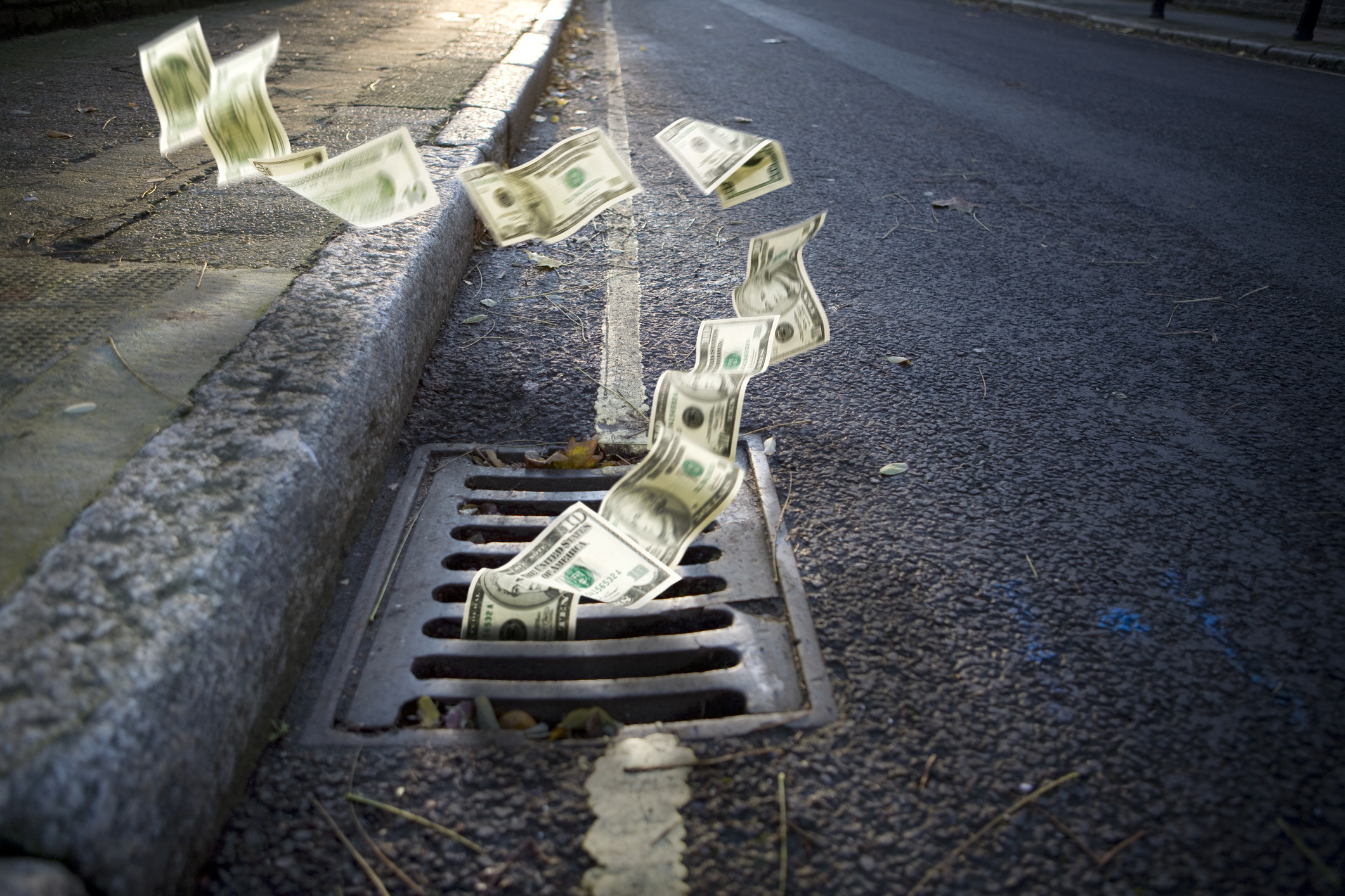 Money falling down a drain.