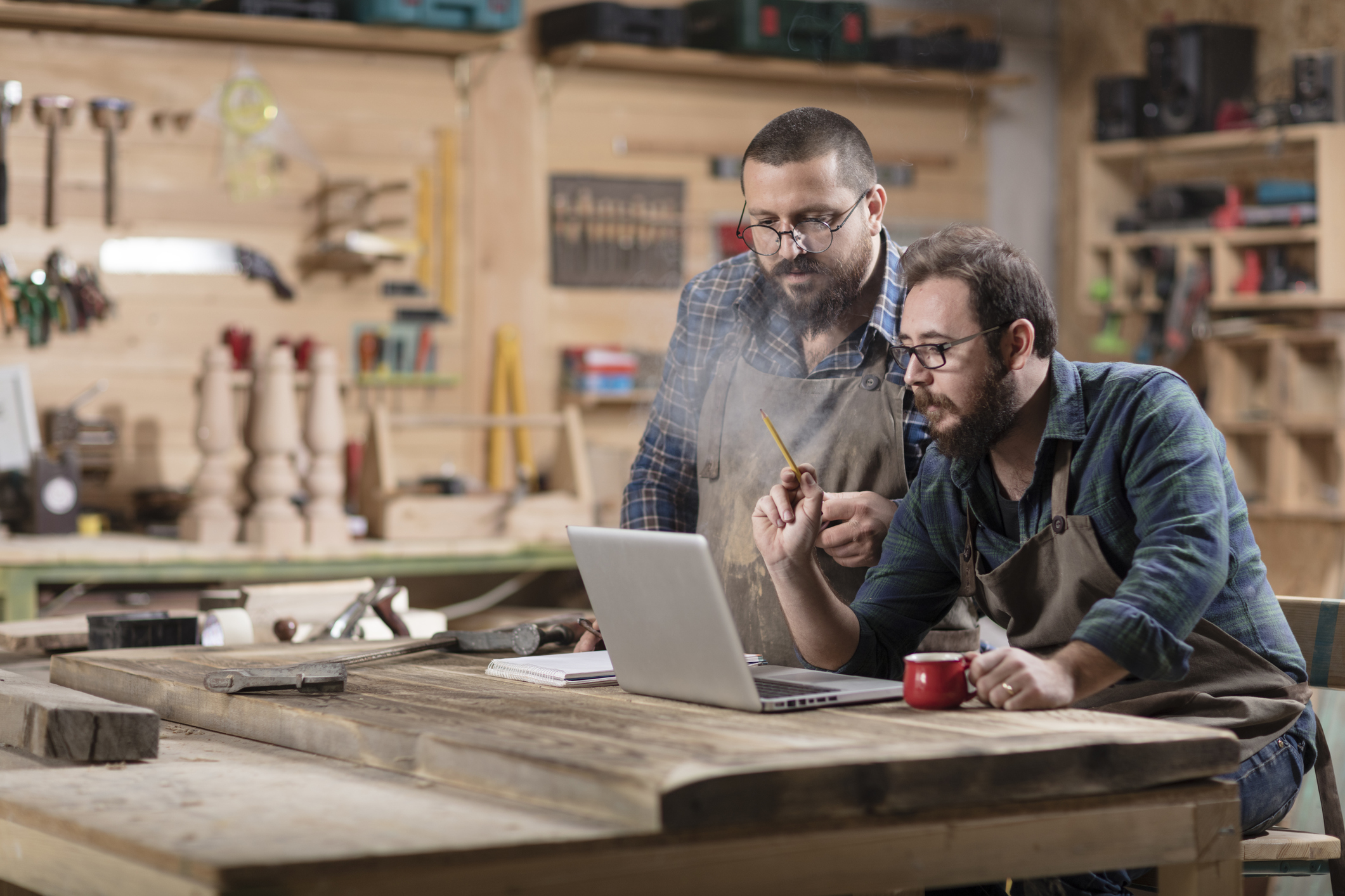 Two people in a wood shop looking at a laptop.