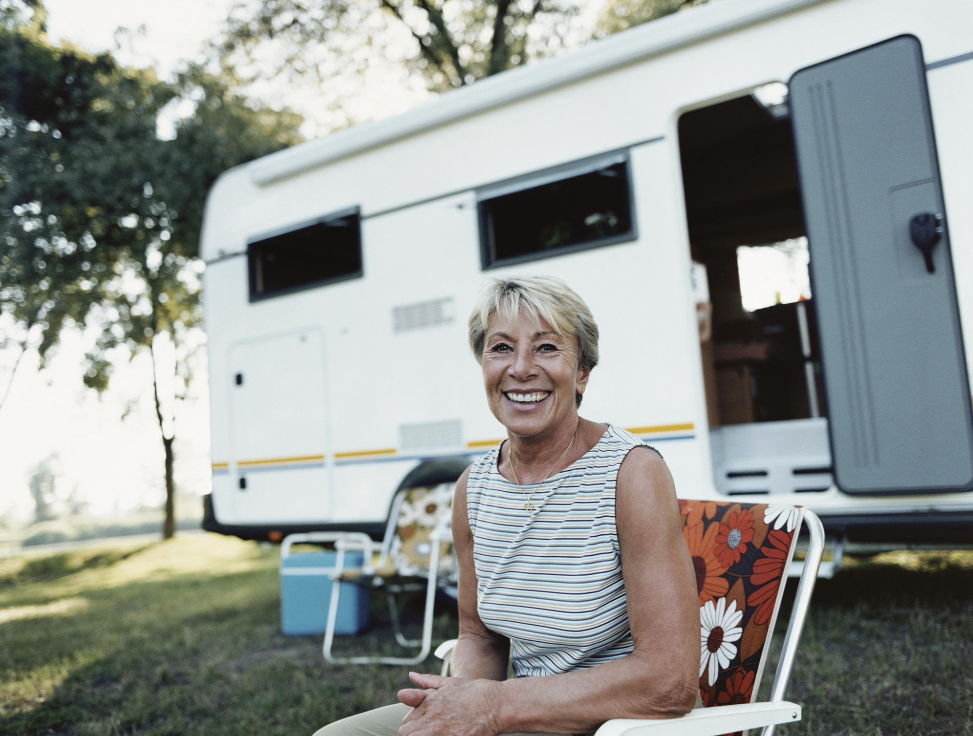 Smiling woman sitting in front of an RV.