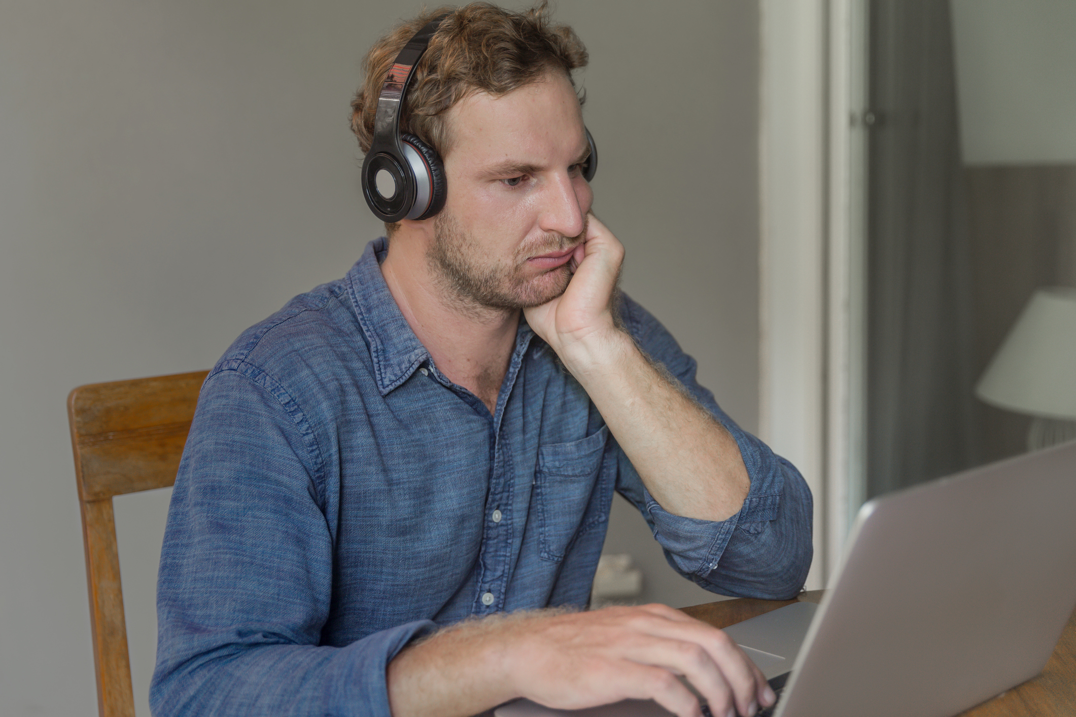 Man at laptop wearing headphones frowning