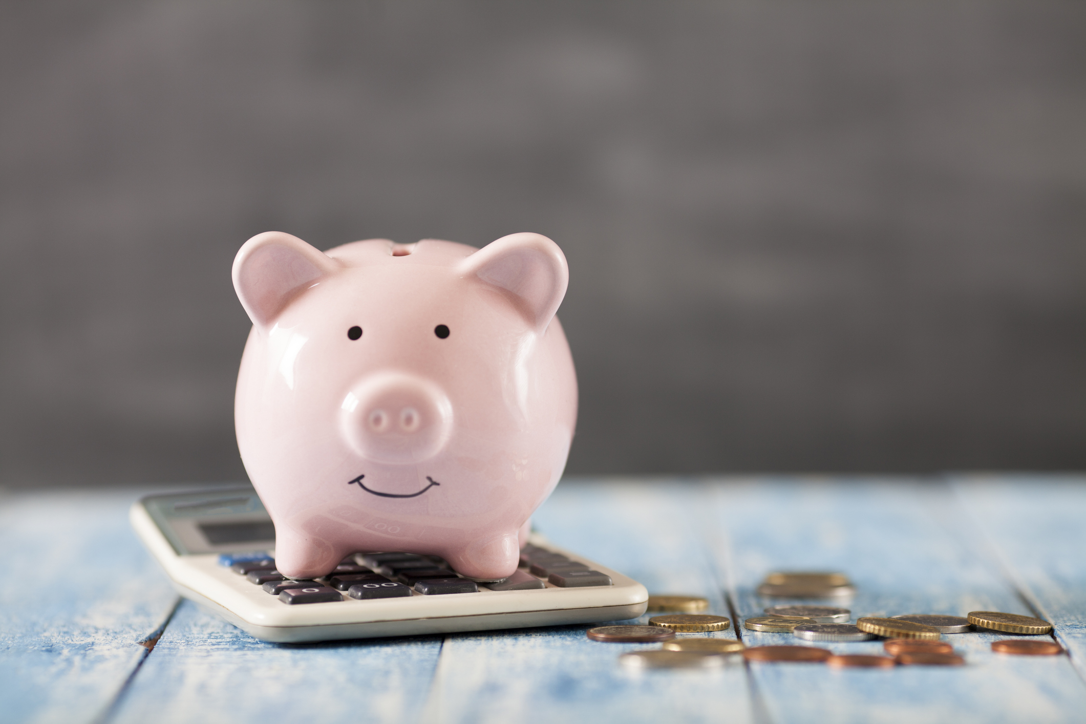 Piggy bank sitting on calculator next to change