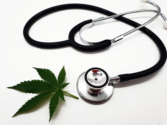 Stethoscope placed next to a marijuana leaf.