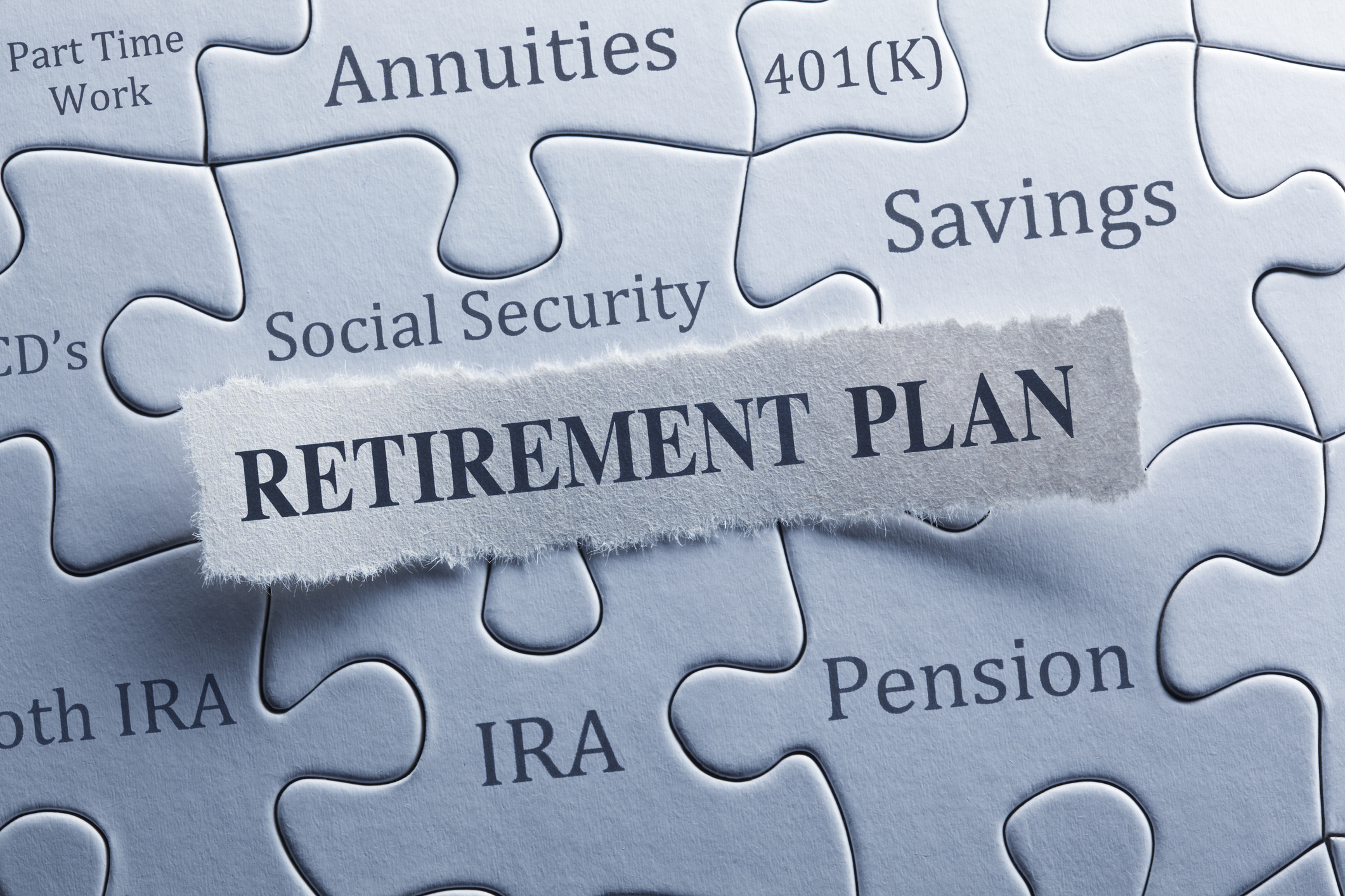 A jigsaw puzzle features words such as social security, IRA, pension, retirement plan.