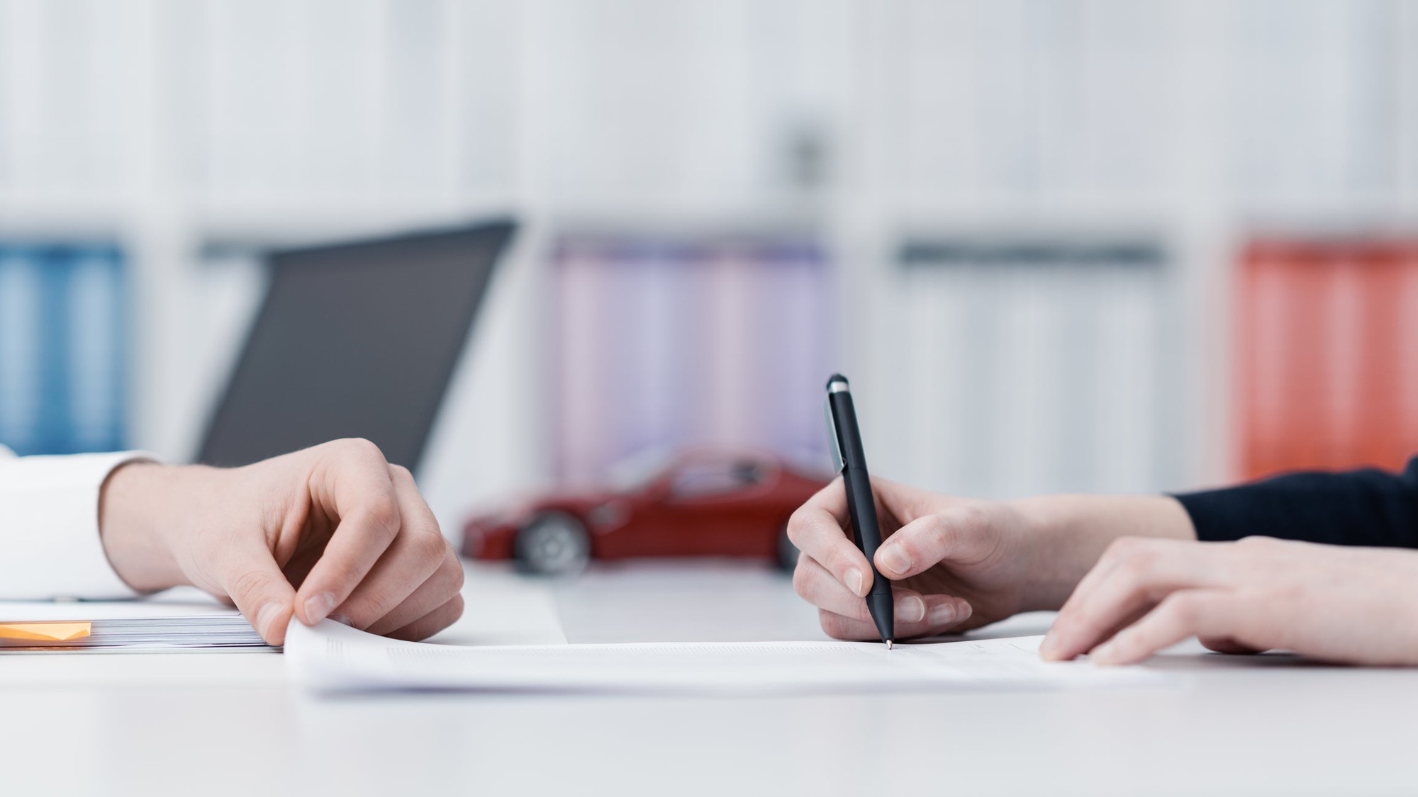 Hands signing paperwork.