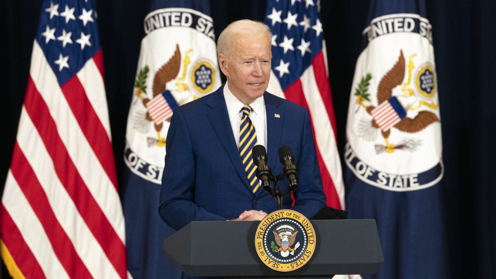 President Biden at podium with flags behind.