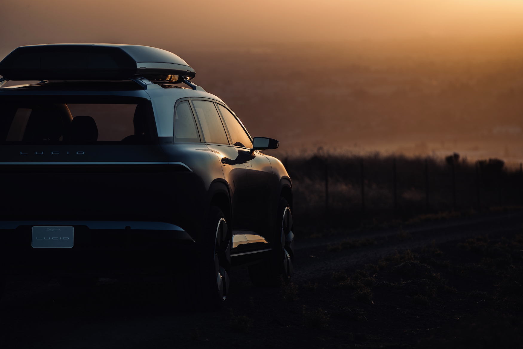 A prototype Lucid SUV, shown in dim light from behind.