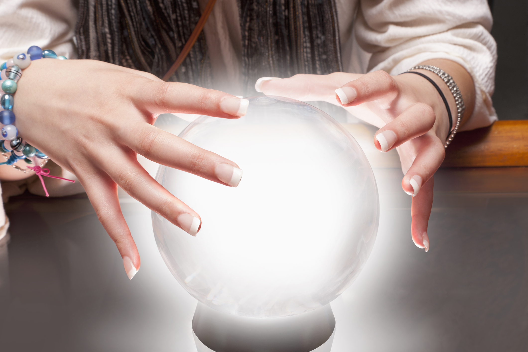 Fortune teller moves hands over a crystal ball