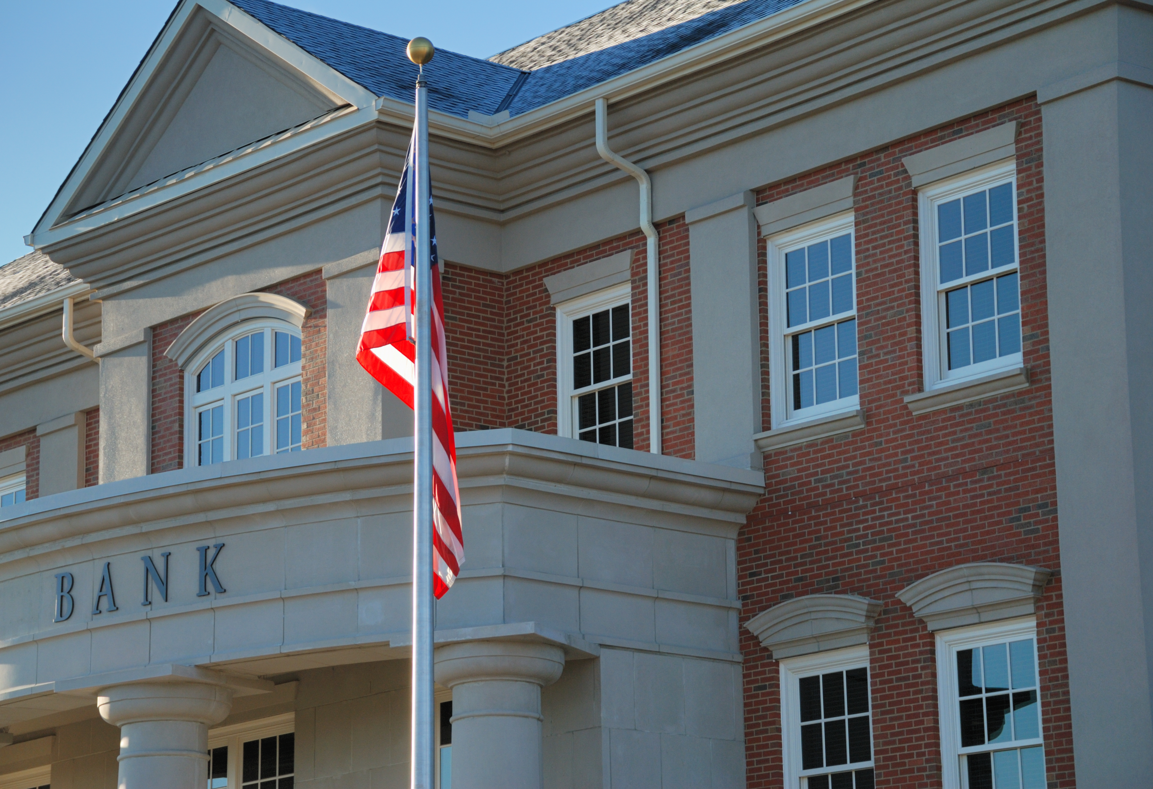 Exterior of a brick bank with an American flag outside.