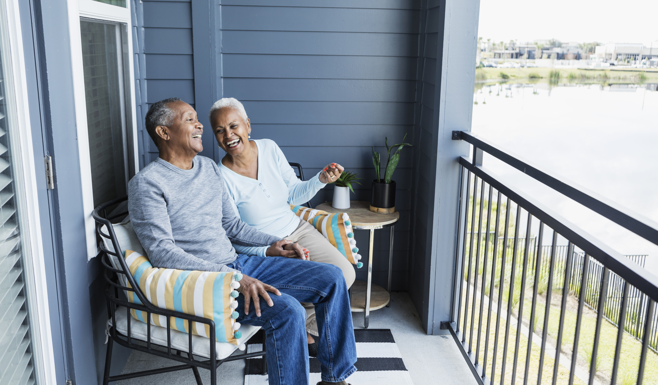 Laughing senior couple sitting on balcony