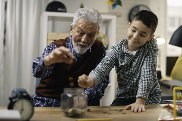Senior man and young boy putting change in jar 