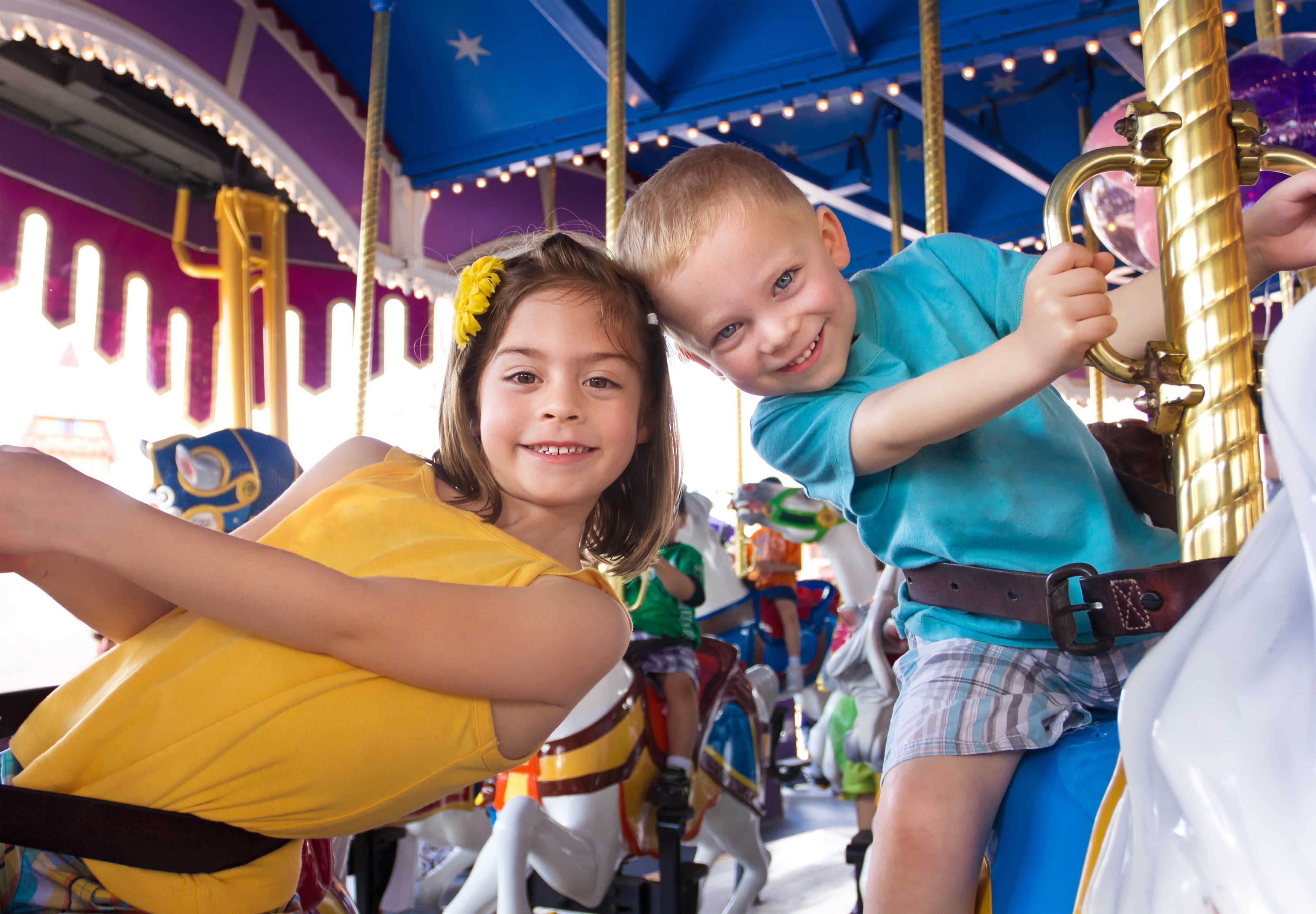 A young boy and girl on a merry-go-round.