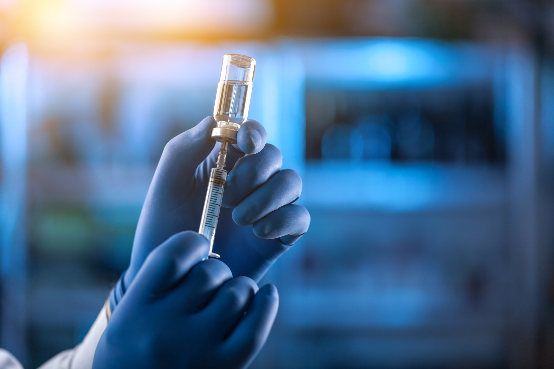 Gloved hands holding syringe and vaccine vial