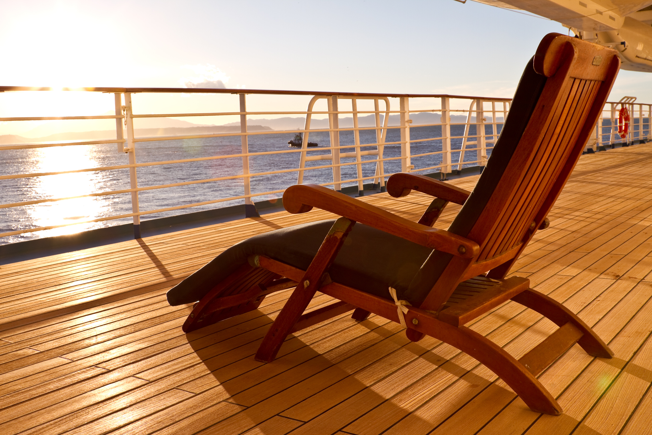 A lounge chair facing the sun on the deck of a cruise ship.