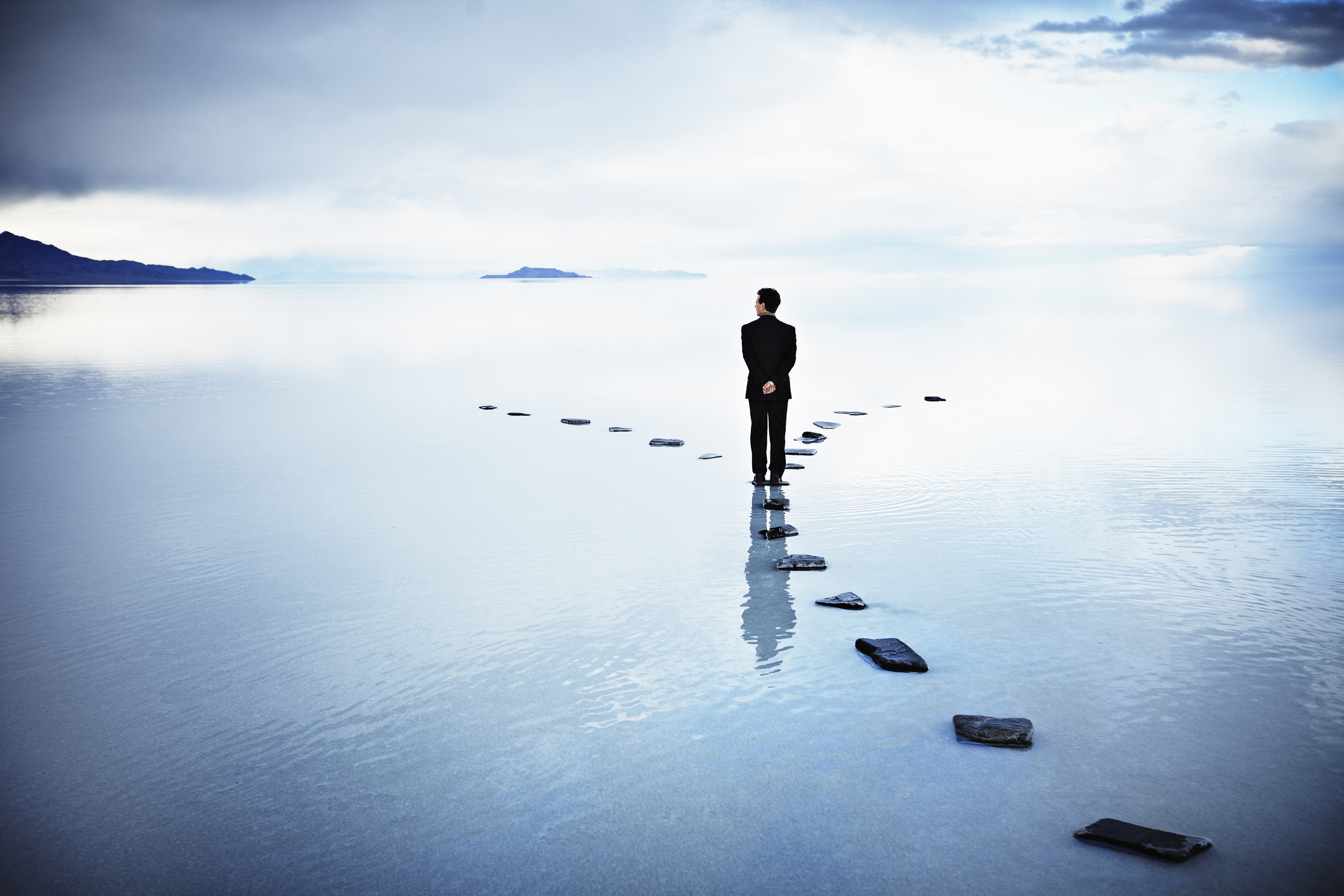 A businessman standing at a stoned pathway.