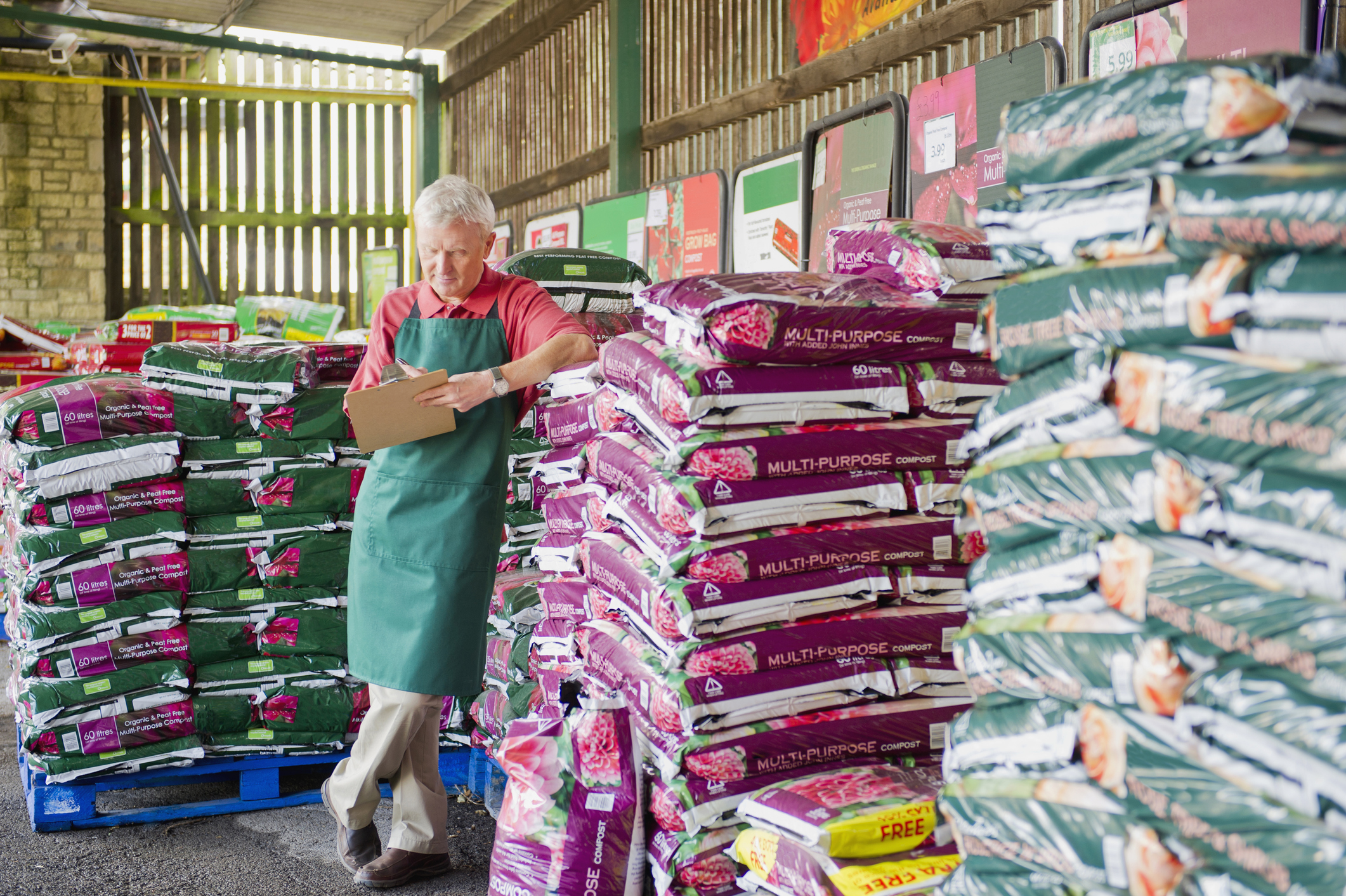 A worker stands near piles of fertilizer in a gardening supply store.