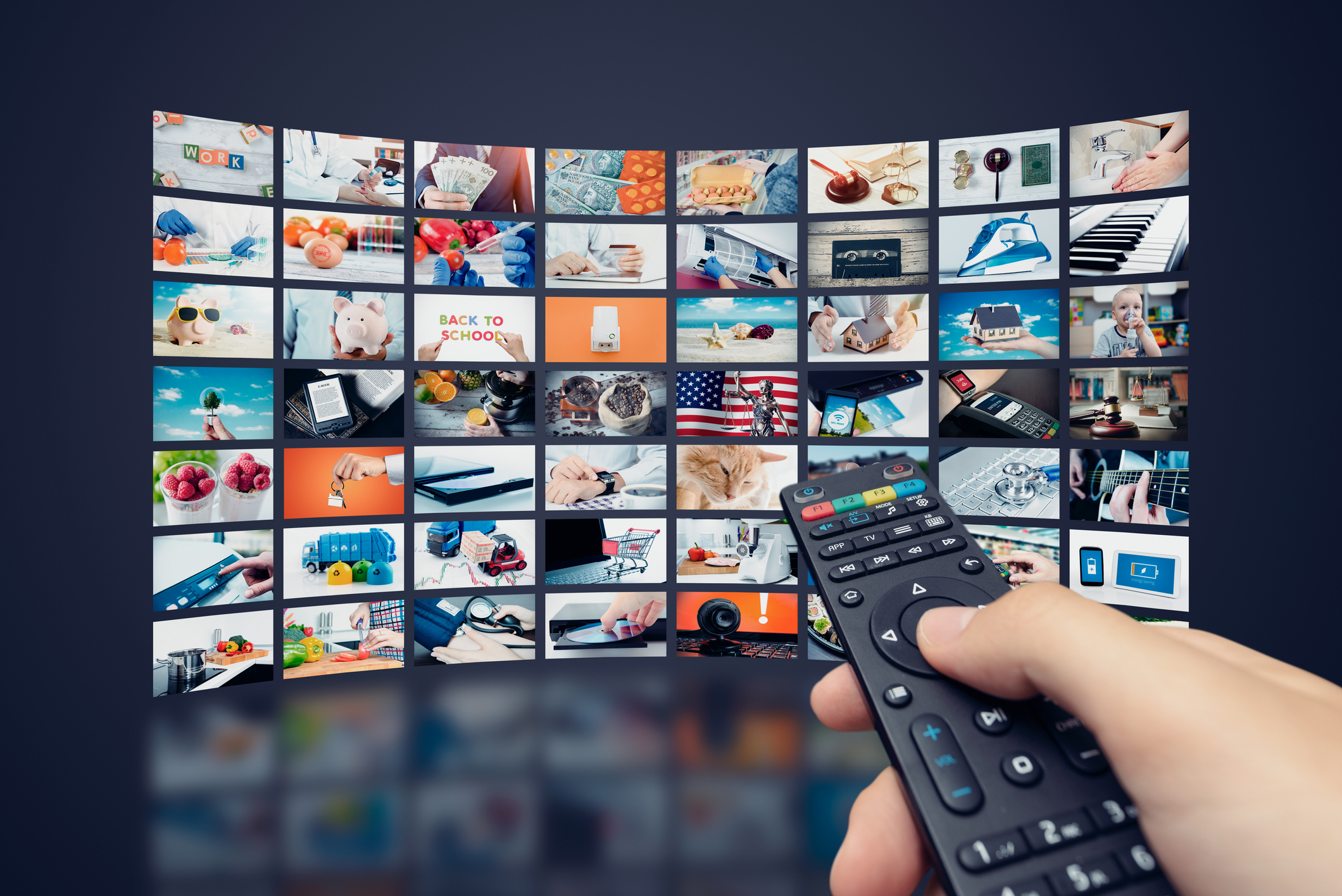 Hand holding TV remote and browsing through a library of videos.