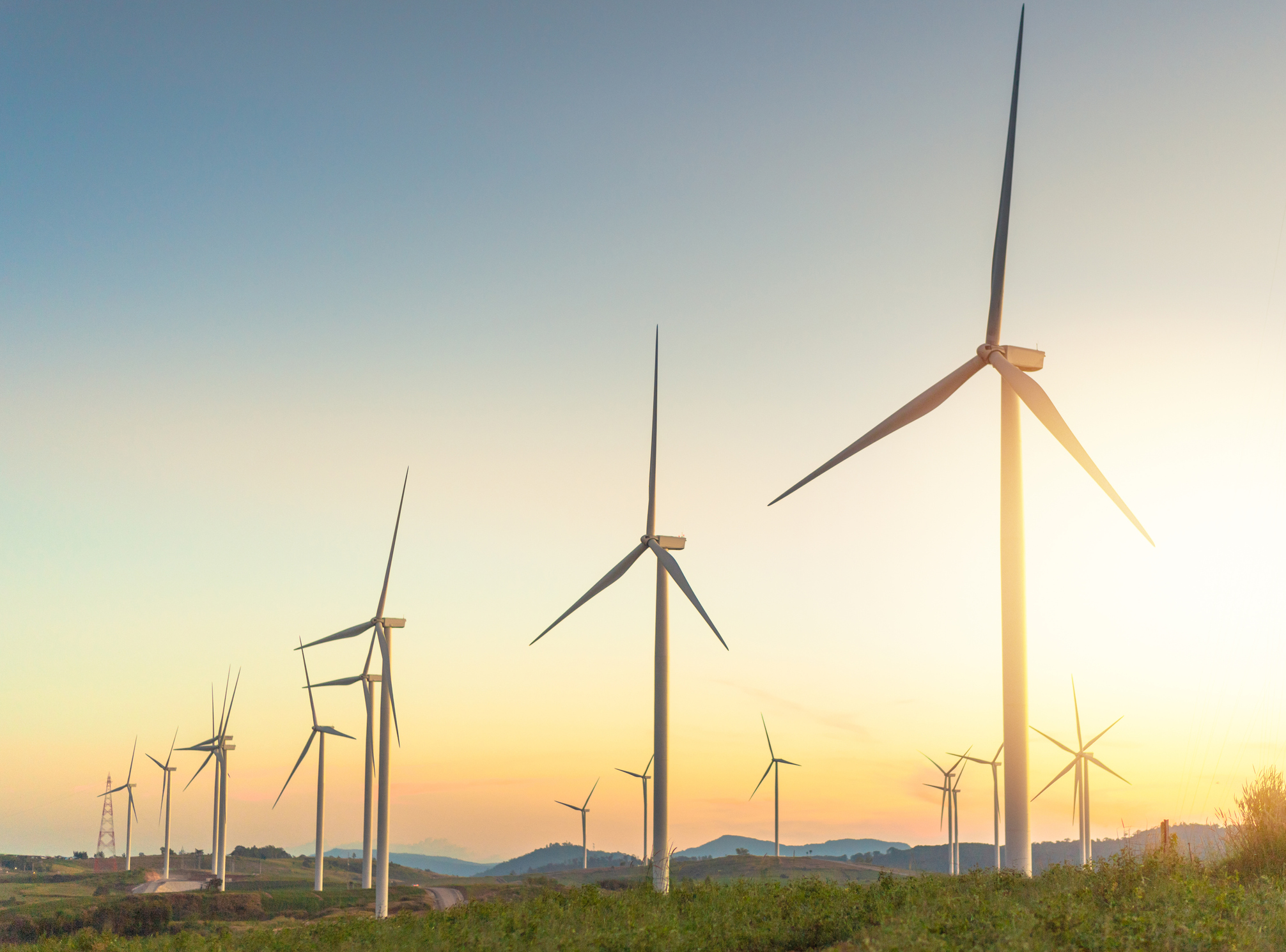 A row of wind turbines at sunrise.